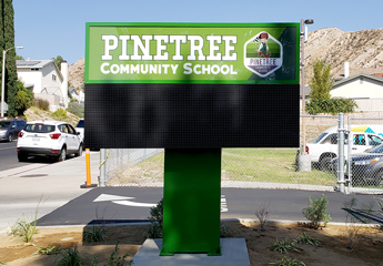 Outdoor single-pole pylon sign displaying school's name and logo