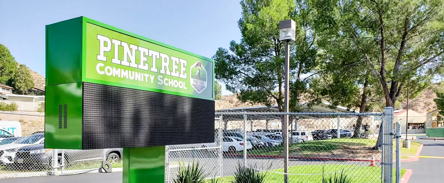 Pinetree Community School pylon sign in green displaying the institution name made of aluminum