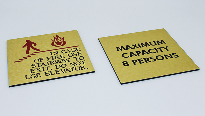 Square-shaped interior signs with black warning notes made of brushed aluminum