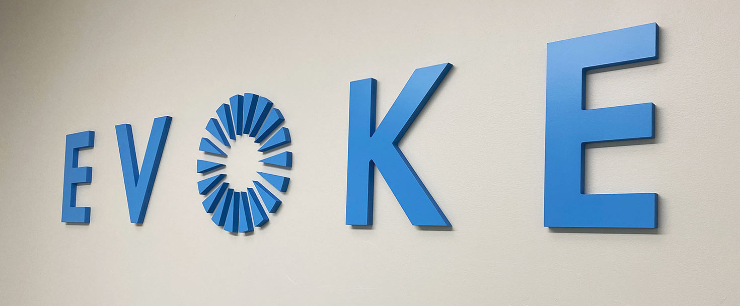 Evoke PVC sign in blue displaying the brand name and logo in letters for interior wall branding