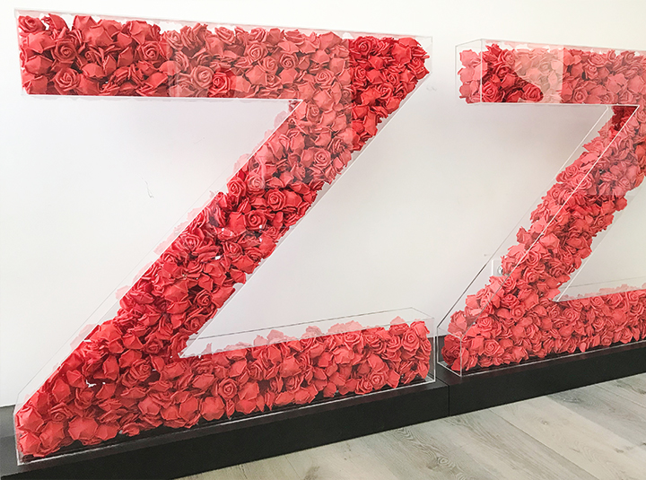 Free-standing custom 3D acrylic letters filled with artificial red roses for business branding