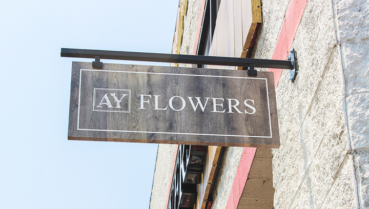 AY Flowers hanging wooden sign displaying the company name and logo for outdoor branding