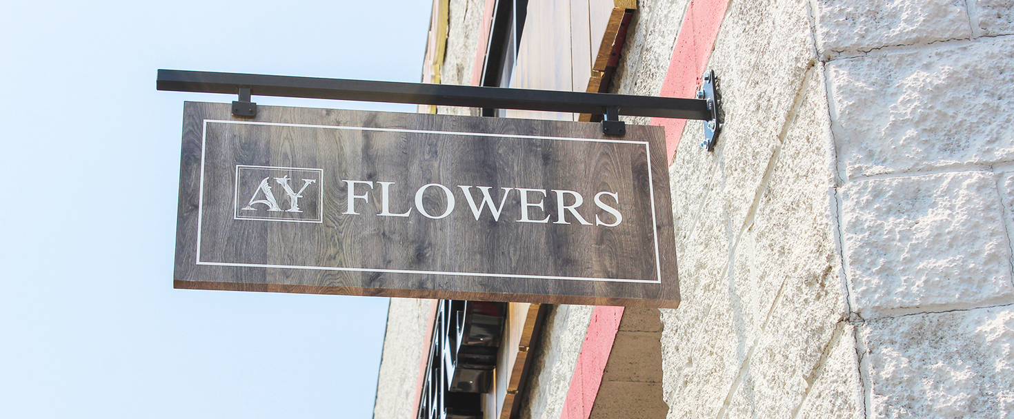 Ay Flowers wooden sign in a hanging style displaying the company name for outdoor branding