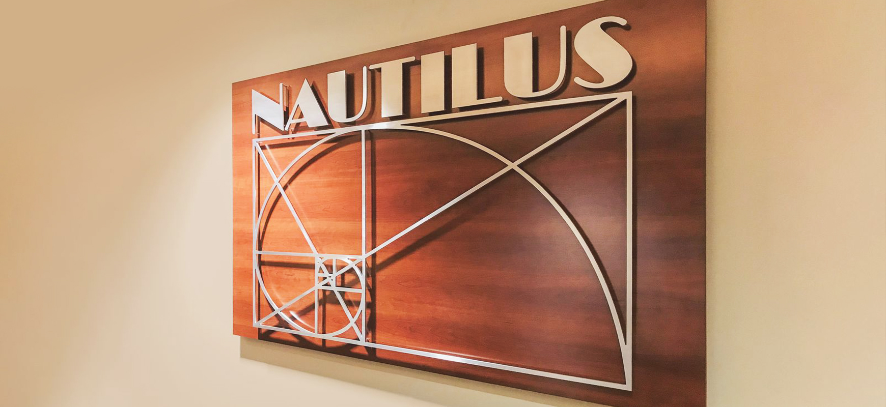 Nautilus wooden sign displaying the company name on a board with a custom decorative element