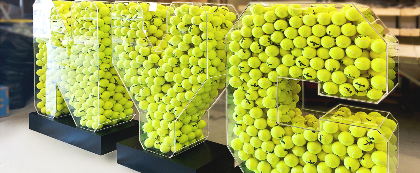 NYC custom acrylic sign with clear letters filled with tennis balls for event branding