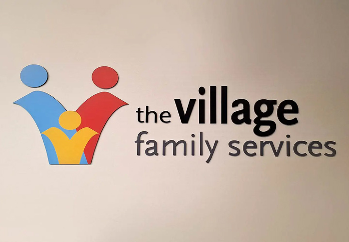 The Village Family Services acrylic sign displaying the company name and logo for branding