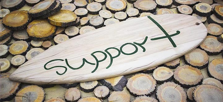 Surfboard-shaped custom wood sign spelling the word Support for rustic office decorating