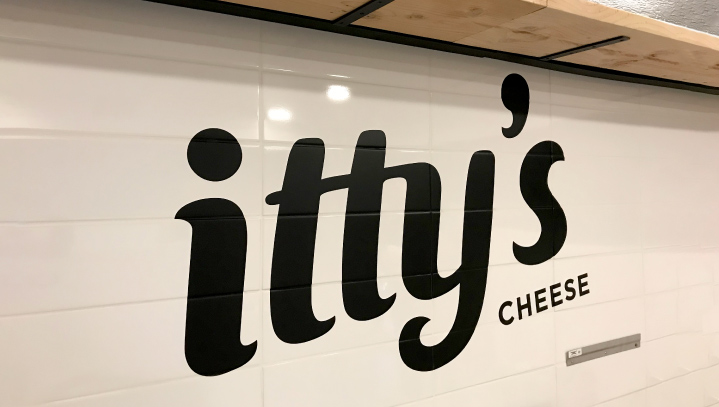 Itty's Cheese custom vinyl lettering in black spelling the brand name out of opaque vinyl