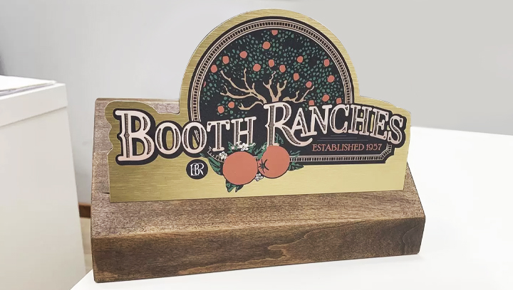 Booth Ranches office desk sign with a custom shape made of wood and brushed aluminum