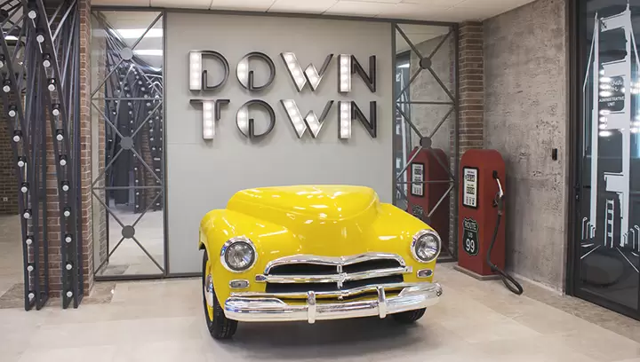 Indoor lobby signs for Down Town featuring a yellow retro car made of aluminum