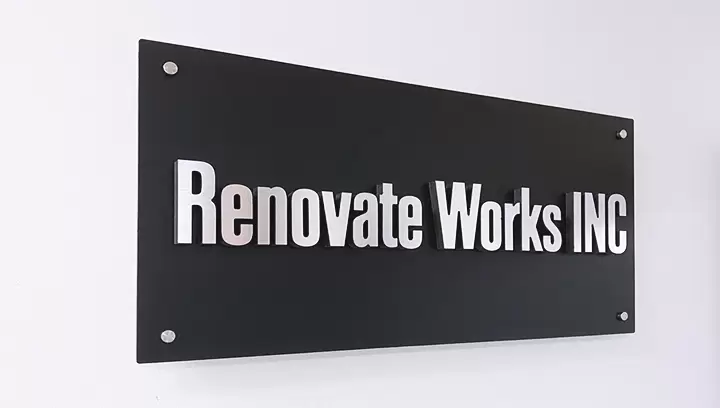 Sleek lobby signs for Renovate Works Inc in silver and black fixed on a wall