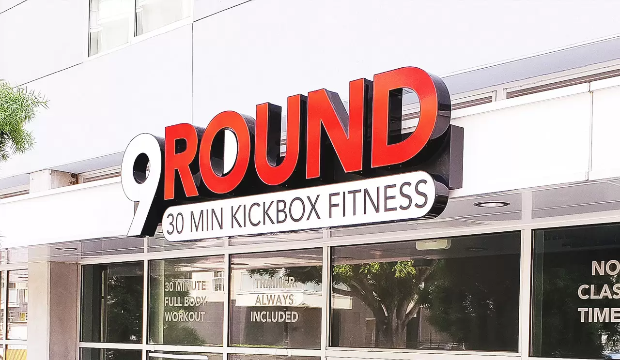 Exterior lobby signs for 9 Round Fitness brand in red and white featuring illumination