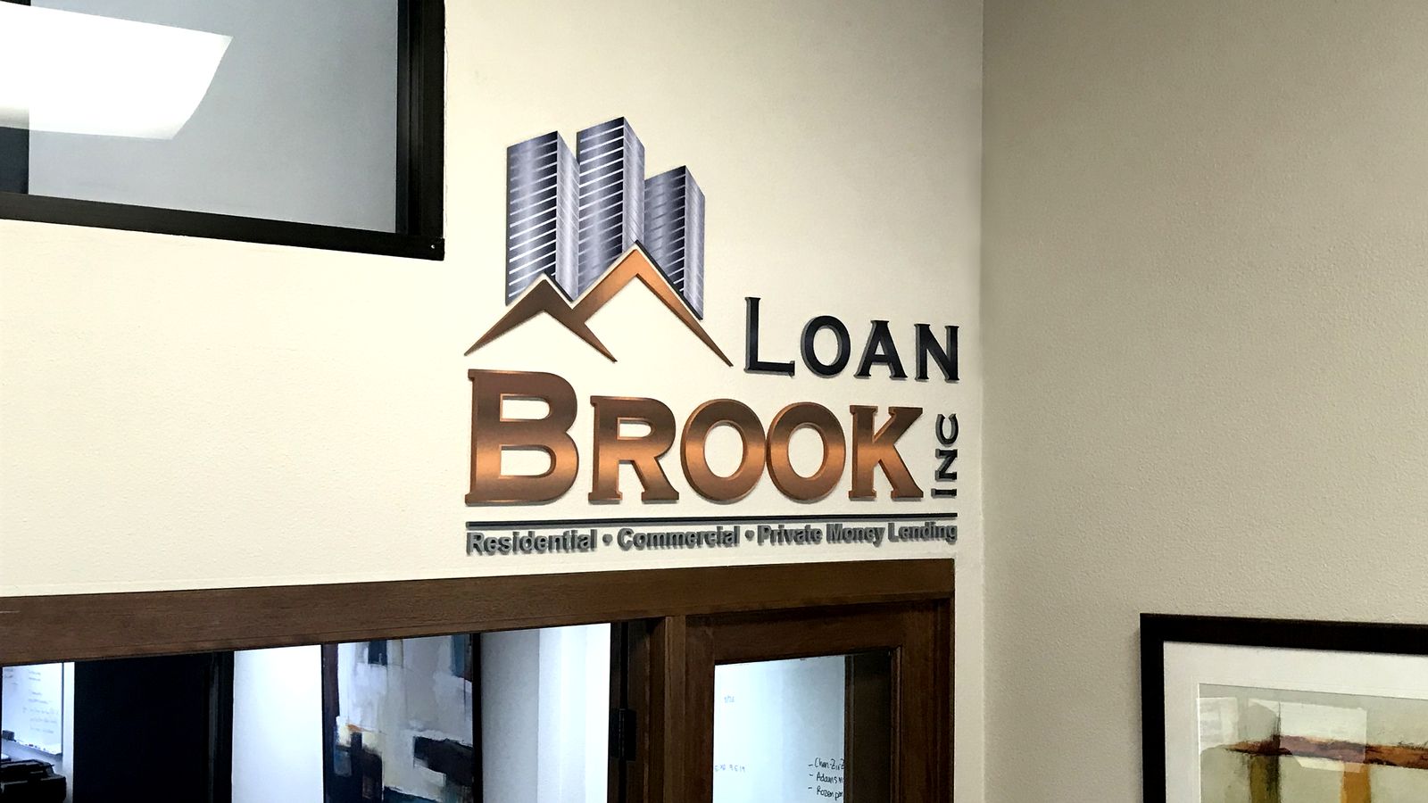 Loan Brook Inc interior business sign with the company name and logo made of painted acrylic