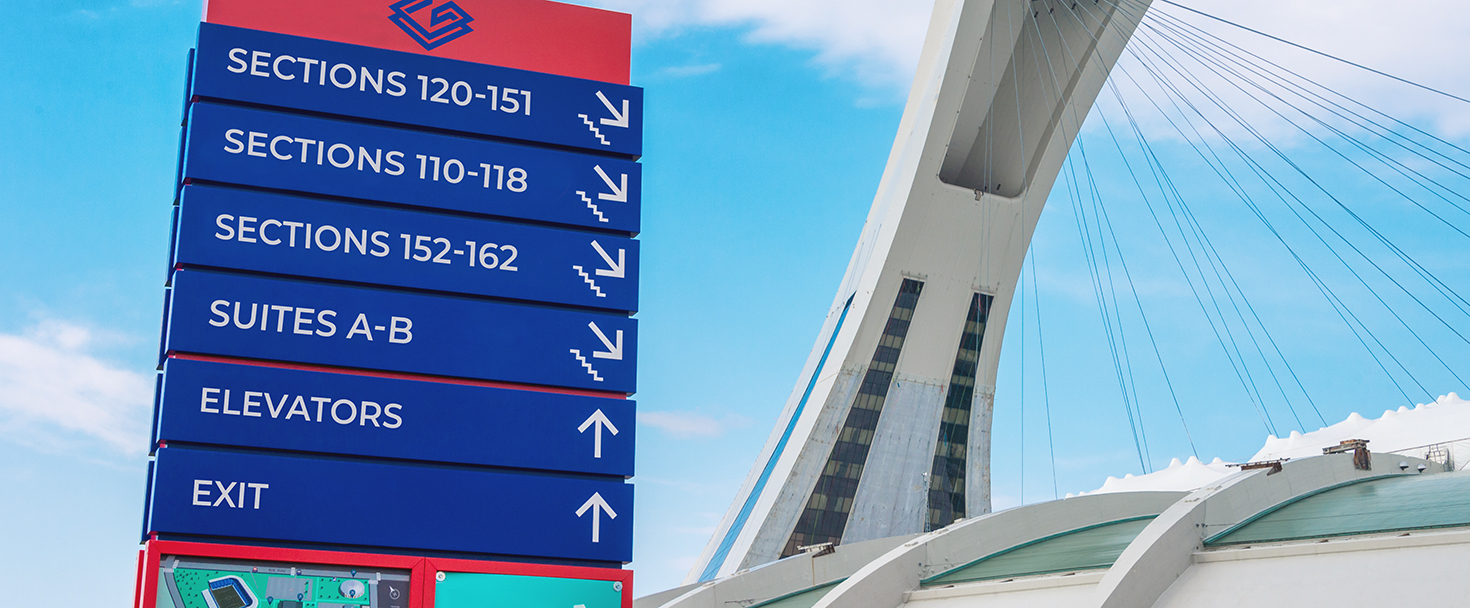 large stadium wayfinding signage in blue and red displayed outdoors