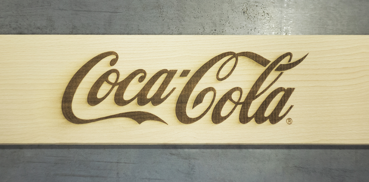 Cool engraving design on wood displaying Coca Cola's brand name