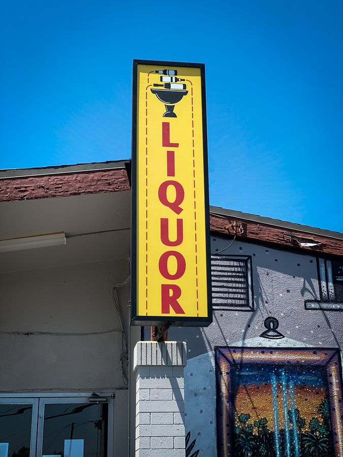 The Liquor outdoor light box in yellow made of aluminum and acrylic for storefront branding