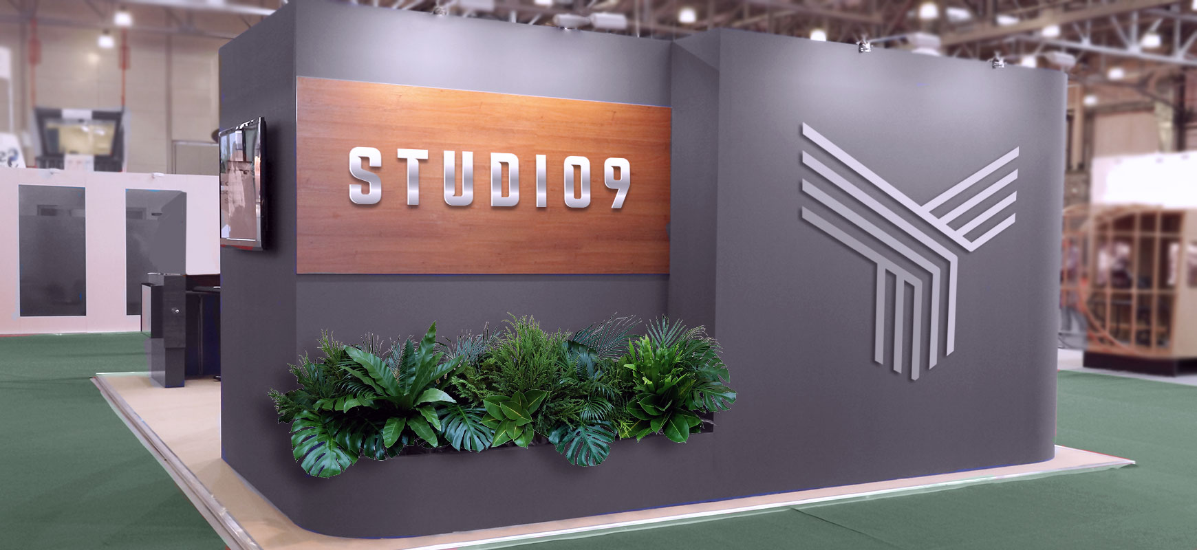 Studio 9 trade show booth display of the brand name and logo over decorative plants