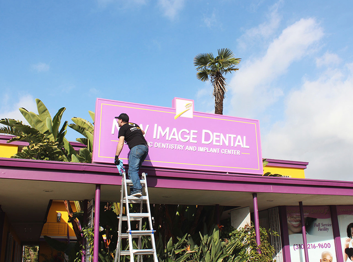 New Image Dental store signs made of aluminum, acrylic and vinyl being installed by an expert