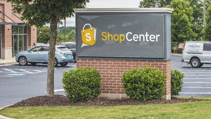 shopping center monument sign displaying the name and logo of the center outdoors