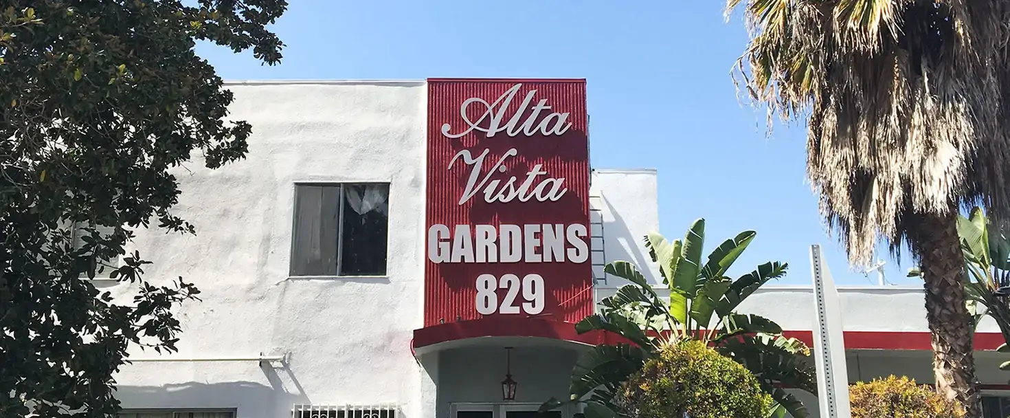Building signage for Alta Vista in white over red installed over the building entrance
