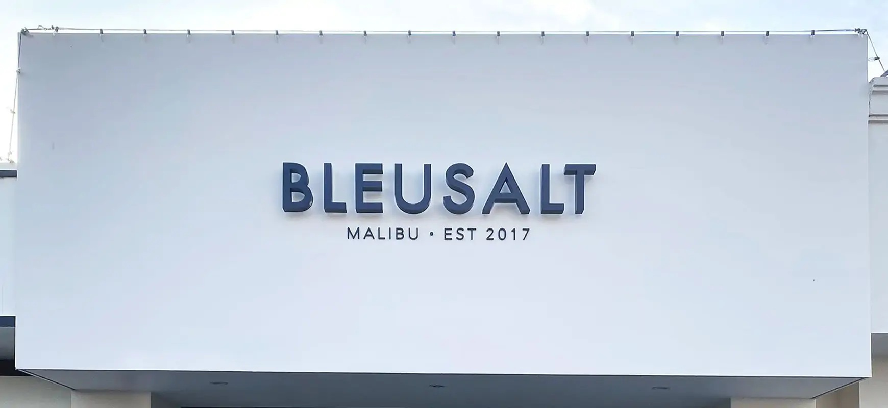 Building signage for Bleusalt installed on building exterior in blue on a white background