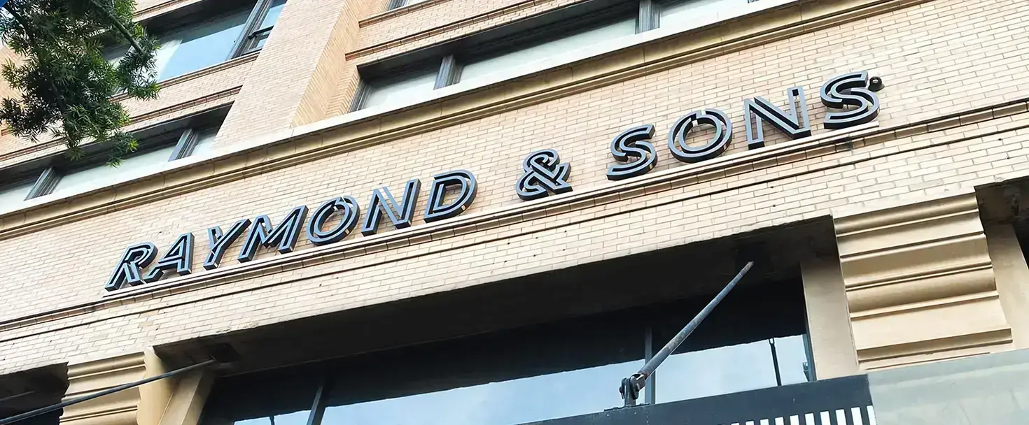 Building signage for Raymound & Sons with 3d components fixed on a brick wall made of aluminum