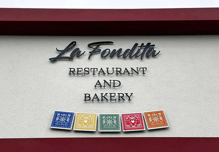 Building sign for La Fondita fixed on a wall with black lettering accompanied by colorful tiles