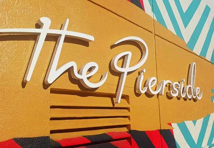 The Pierside exterior building sign in white displaying the brand logo made of aluminum