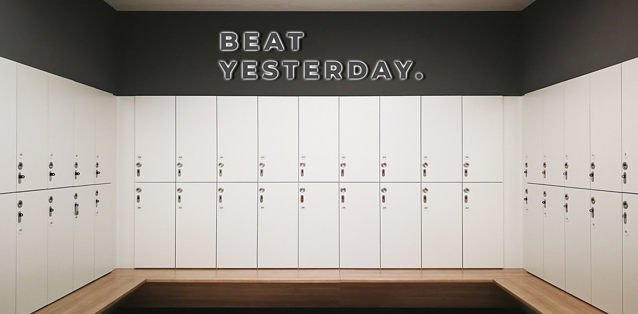 Illuminated gym locker room design idea displaying a motivational phrase