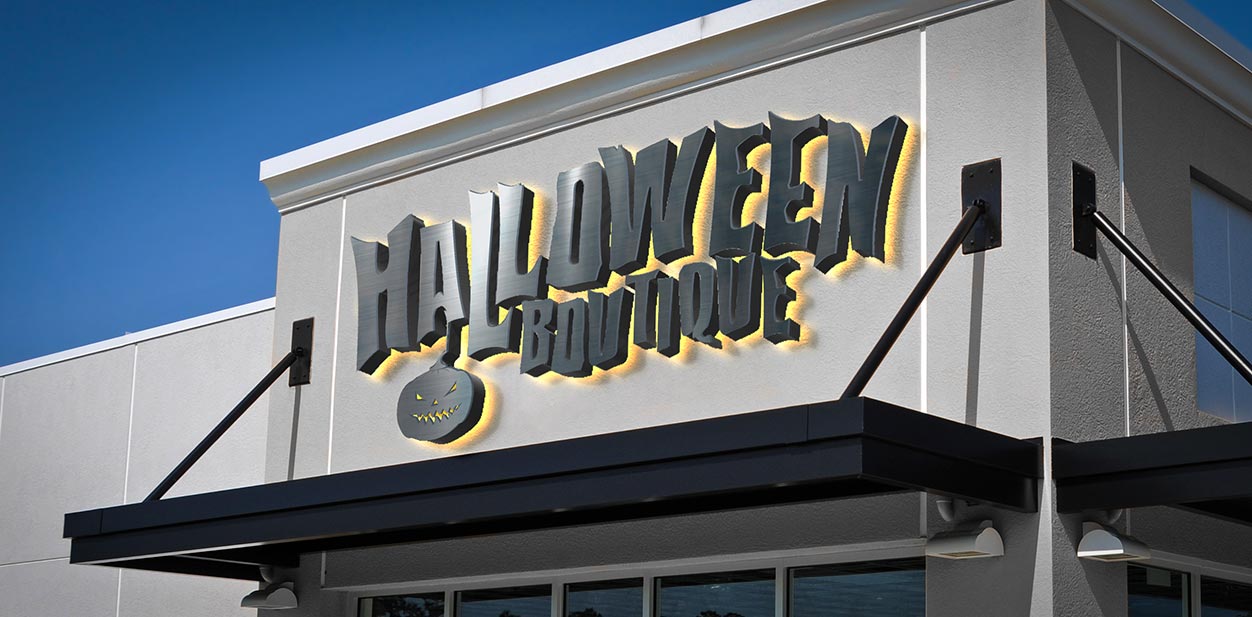 Lighted Halloween storefront sign in black displaying the boutique name