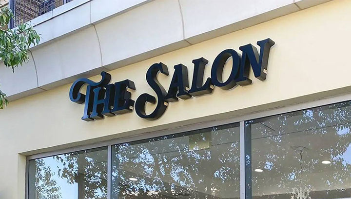 Black outdoor salon sign displaying the brand name