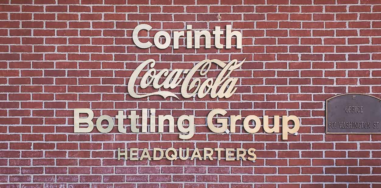 Coca Cola's exterior brick wall design with aluminum letters shaping company's name in golden colors
