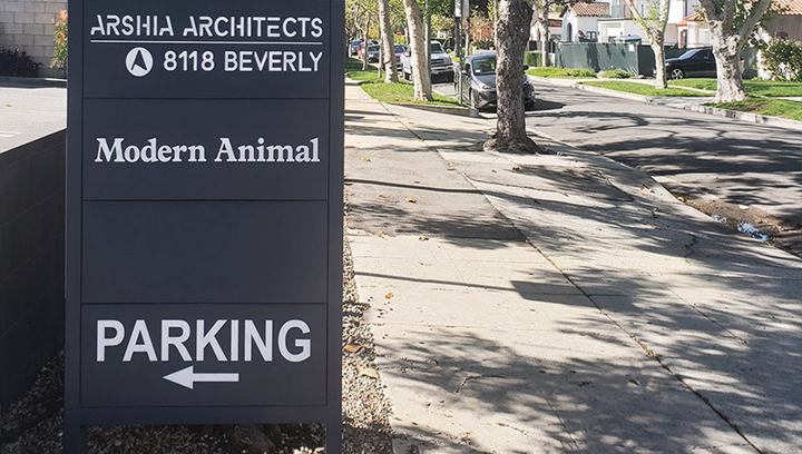 Huge PVC directional sign in black pointing at the parking