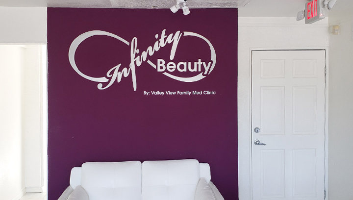 Infinity Beauty salon name sign displayed on a pink wall