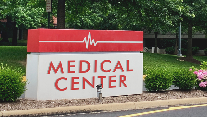 Red and white colored monumental medical board displayed outdoors