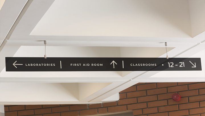 Campus wayfinding signage hung from the college ceiling and showing directions