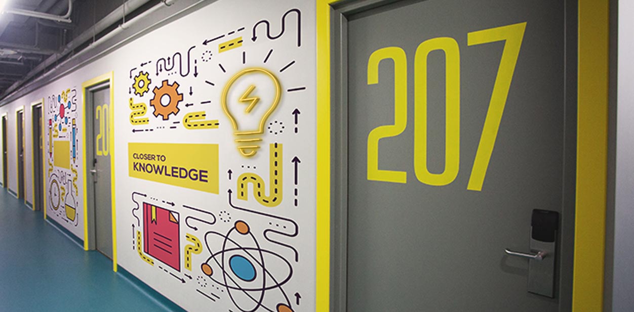 Campus hallway wall signage design with colorful graphics featuring 'Closer to Knowledge' writing