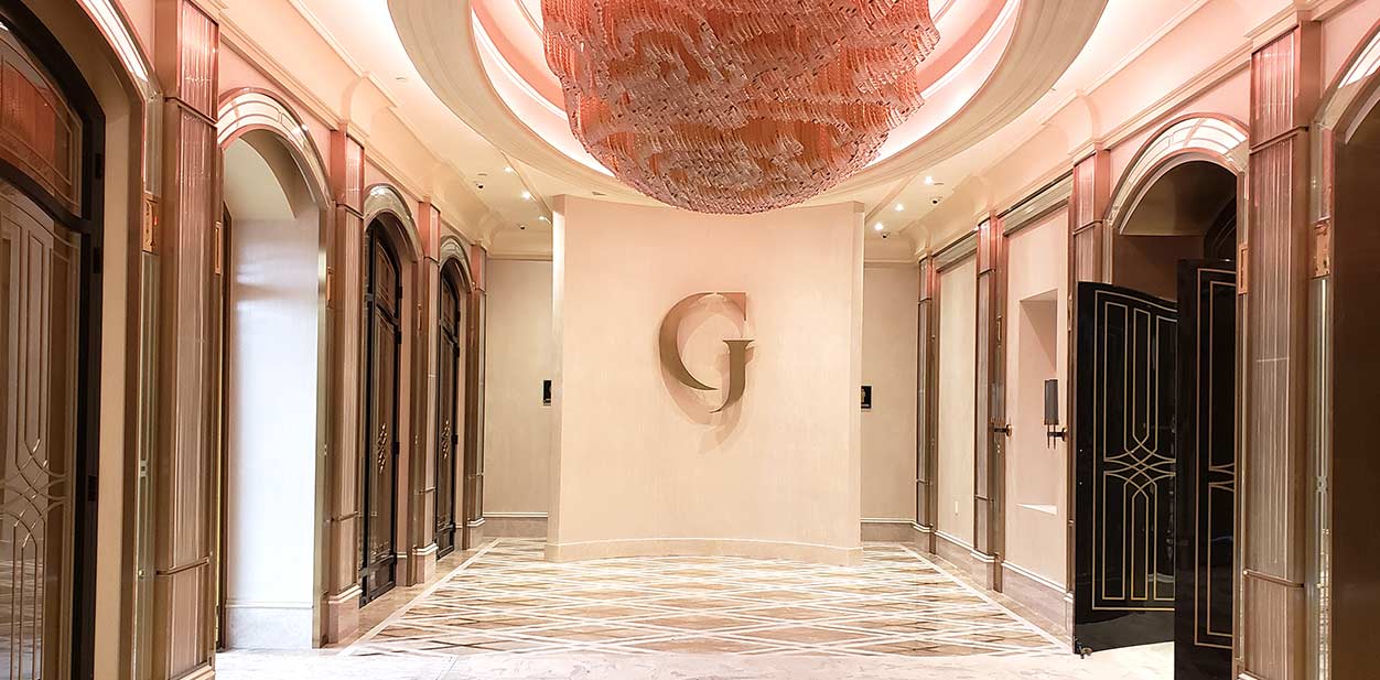 Luxury hospitality branding with an aluminum G-shaped design element and a striking chandelier