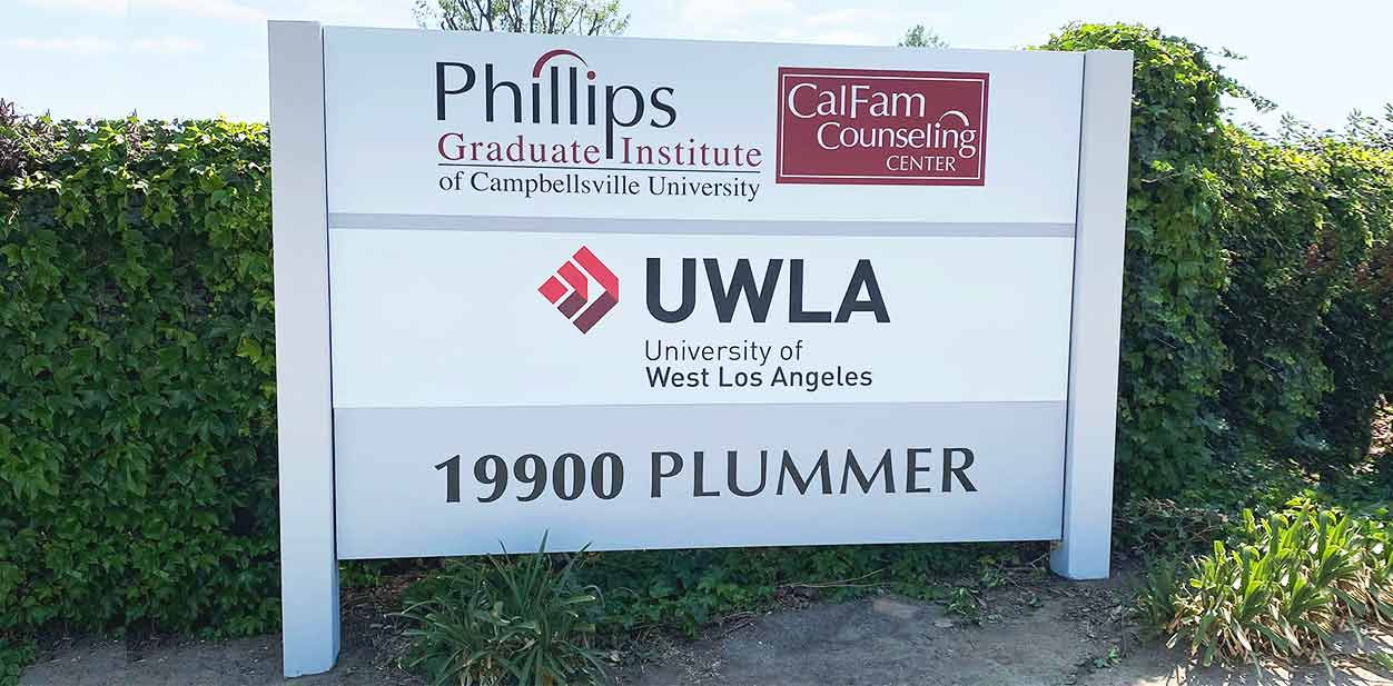 University branding advertising display fixed in the ground and surrounded by bushes