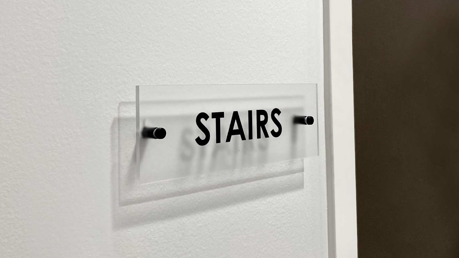 Directional acrylic sign with standoffs