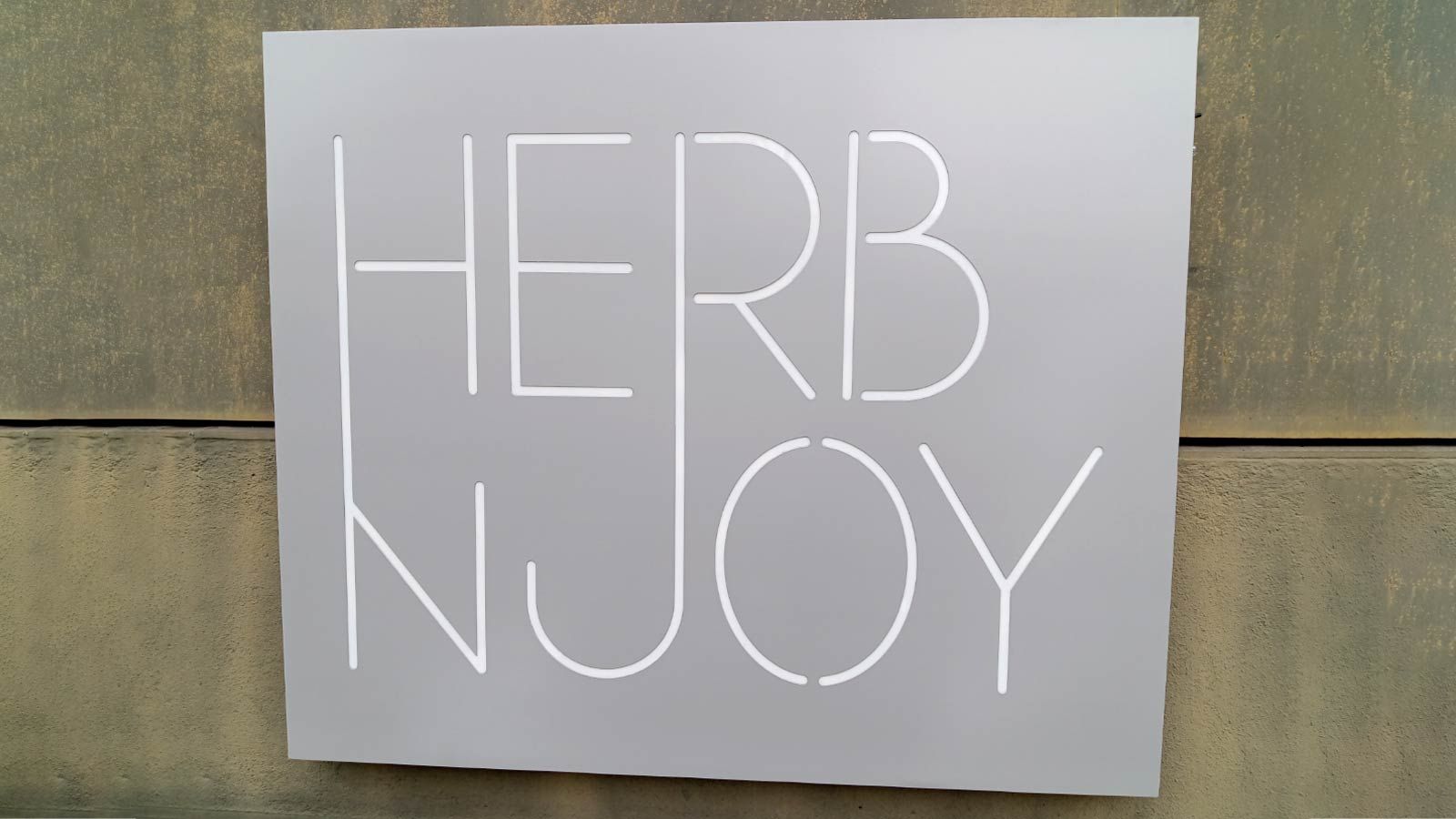 HerbNJoy light up signage mounted to the exterior wall