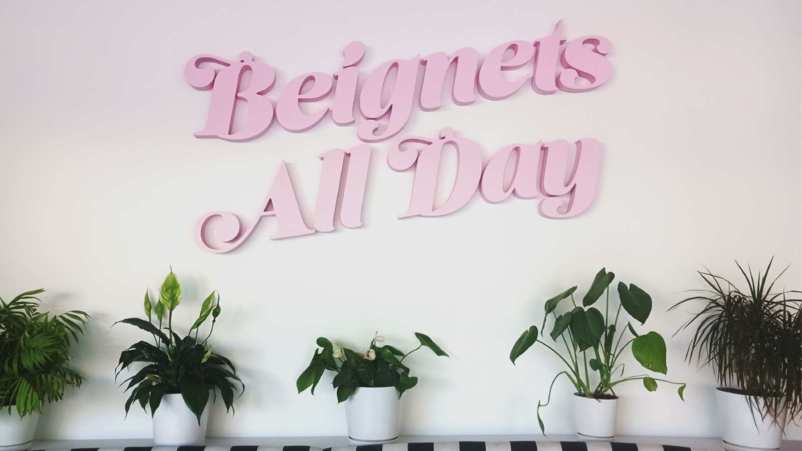 Beignets All Day interior sign attached to the wall