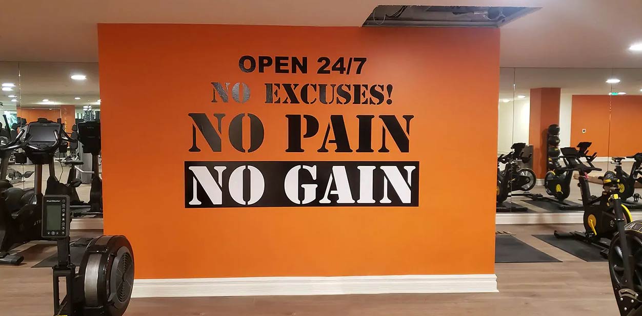 Gym feature wall with black and white inspirational text on orange background