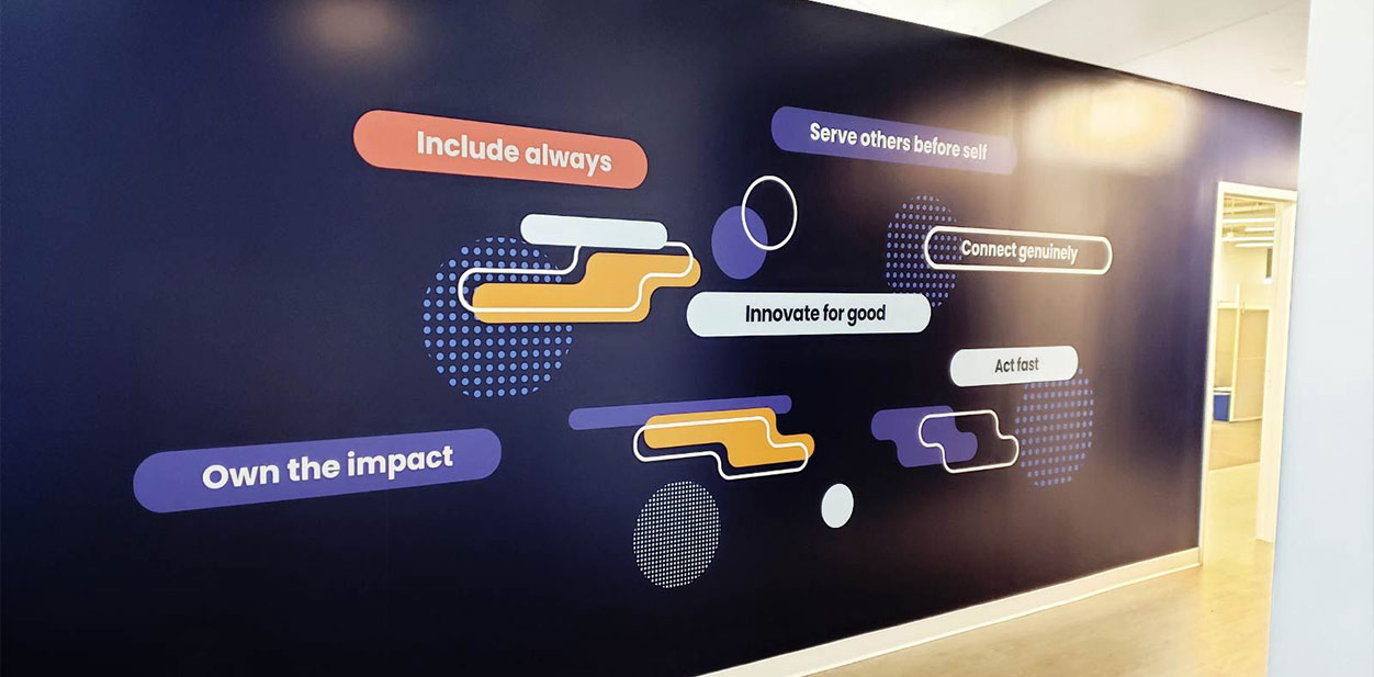 Dark purple office accent wall design displaying motivational branding phrases