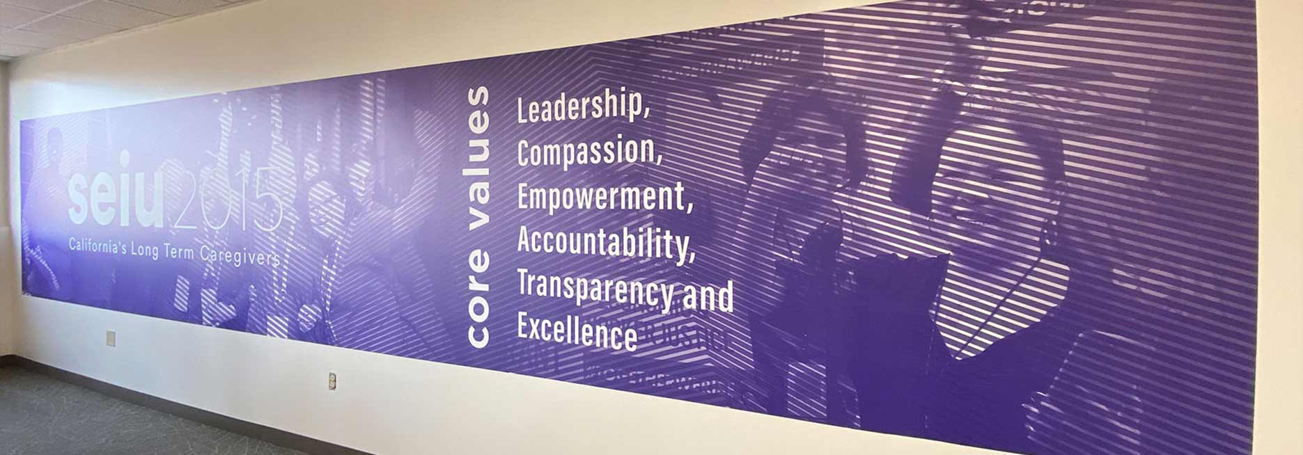 Purple striped office accent wall displaying brand values and team photos