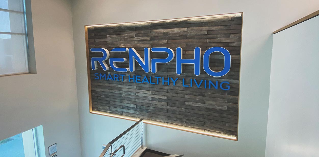 Renpho dimensional accent wall design with blue brand name letters installed on a wooden panel