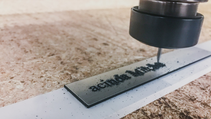 High-speed CNC engraving process on a sheet of aluminum with letter carving