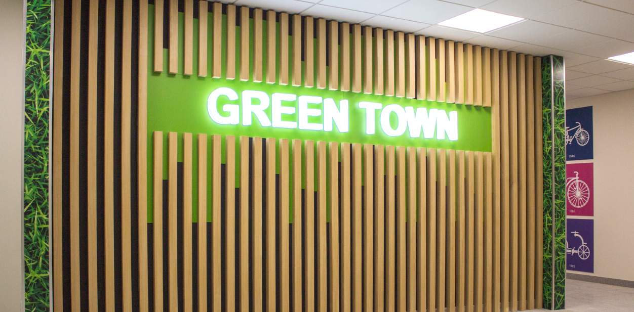 Green Town wood accent wall design with illuminated brand name display and green elements