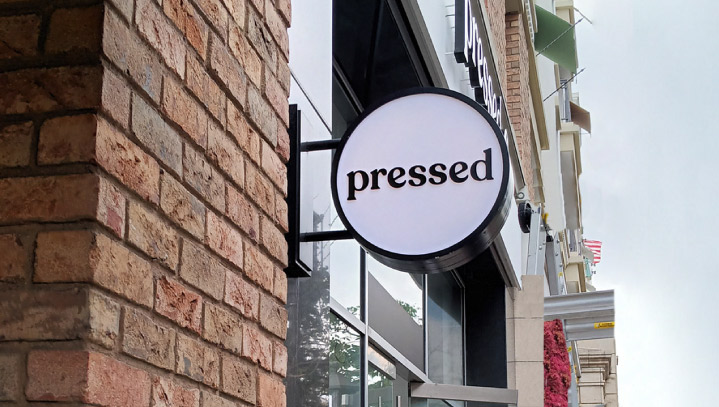 Pressed Juicery illuminated sign installation on an outdoor wall