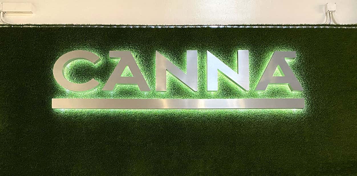 Canna LED metal wall art displayed on an artificial grass for interior branding